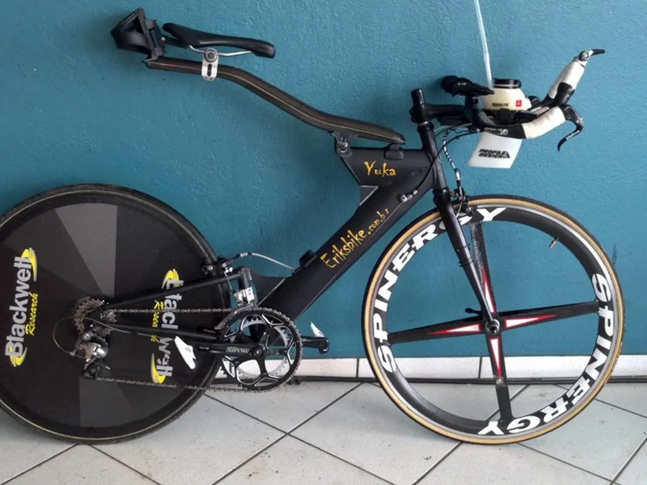 In this image there is a sports bicycle. There is a marble flooring. There is a wall.