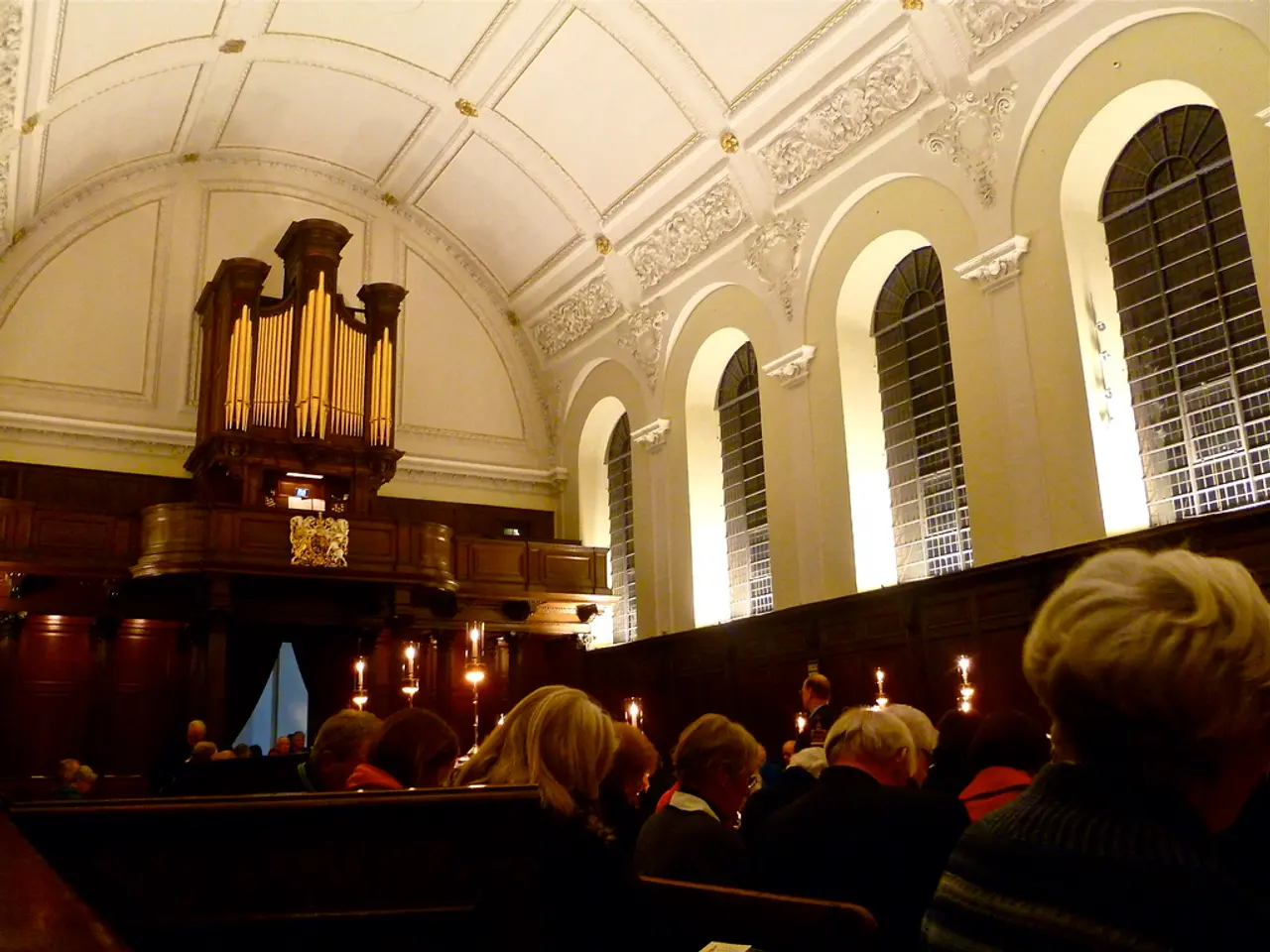 This is the inside view of a church were we can see men and women are sitting and in front of them...