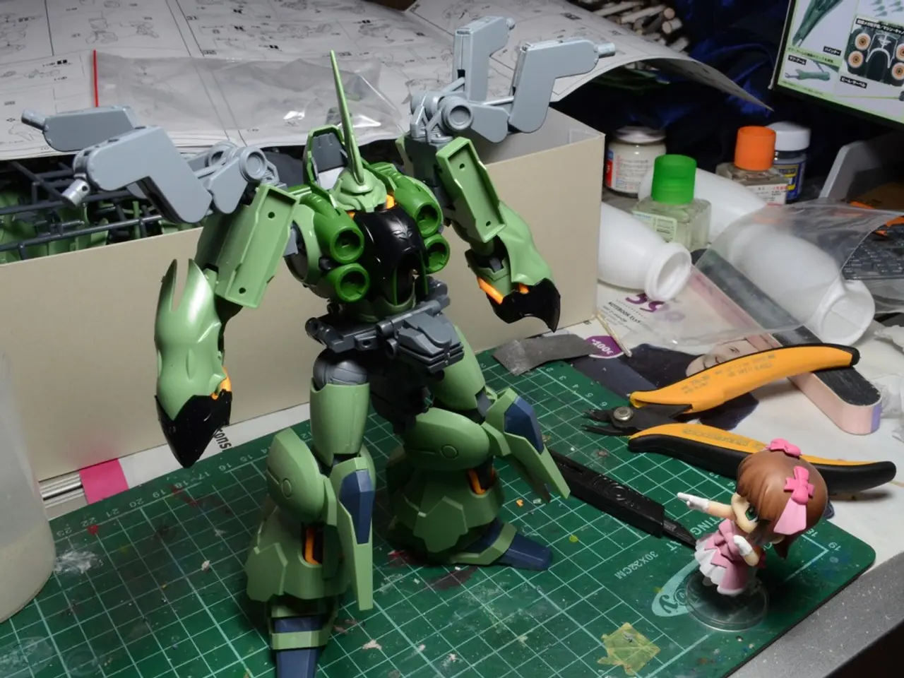 In this image we can see toys, a cutter, box, few bottles, a screen, papers and few other objects...