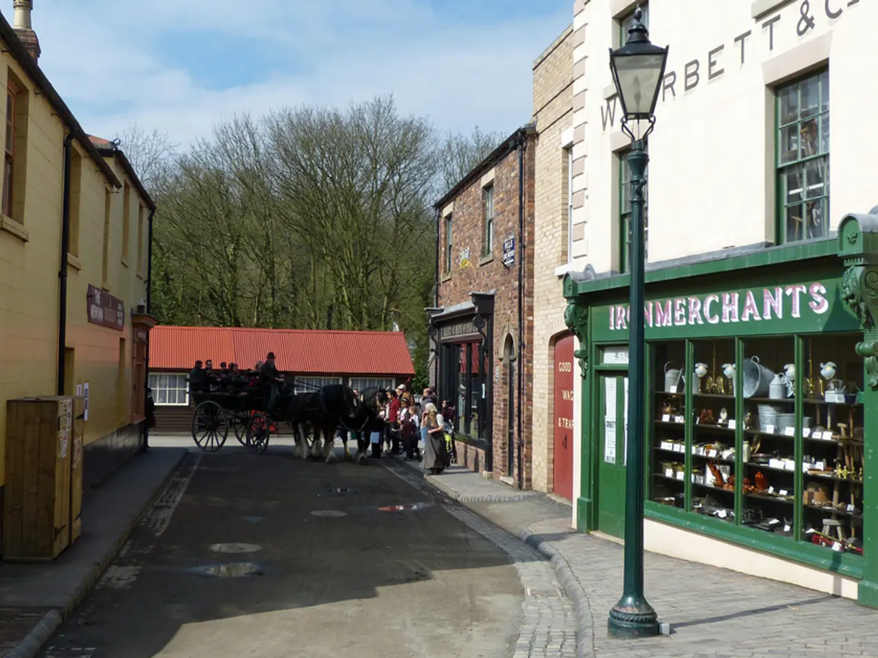 There is a road. On the road there is a horse cart. On that there are many people. On the sides of...