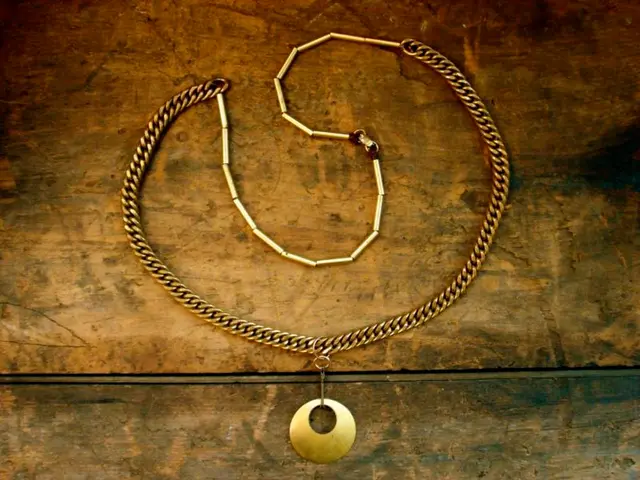 In the image there is a necklace with pendant on a wooden table.