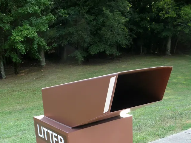 In this image there is a brown box on which litter is written. There is grass and trees at the...